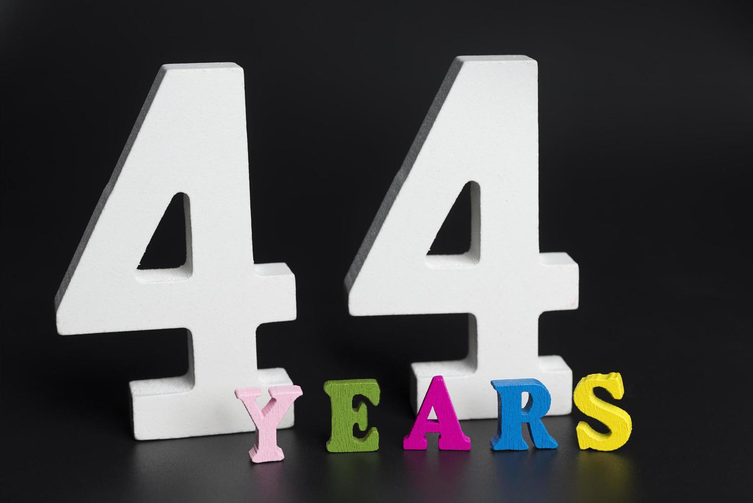 Letters and numbers forty-four years on a black background. photo
