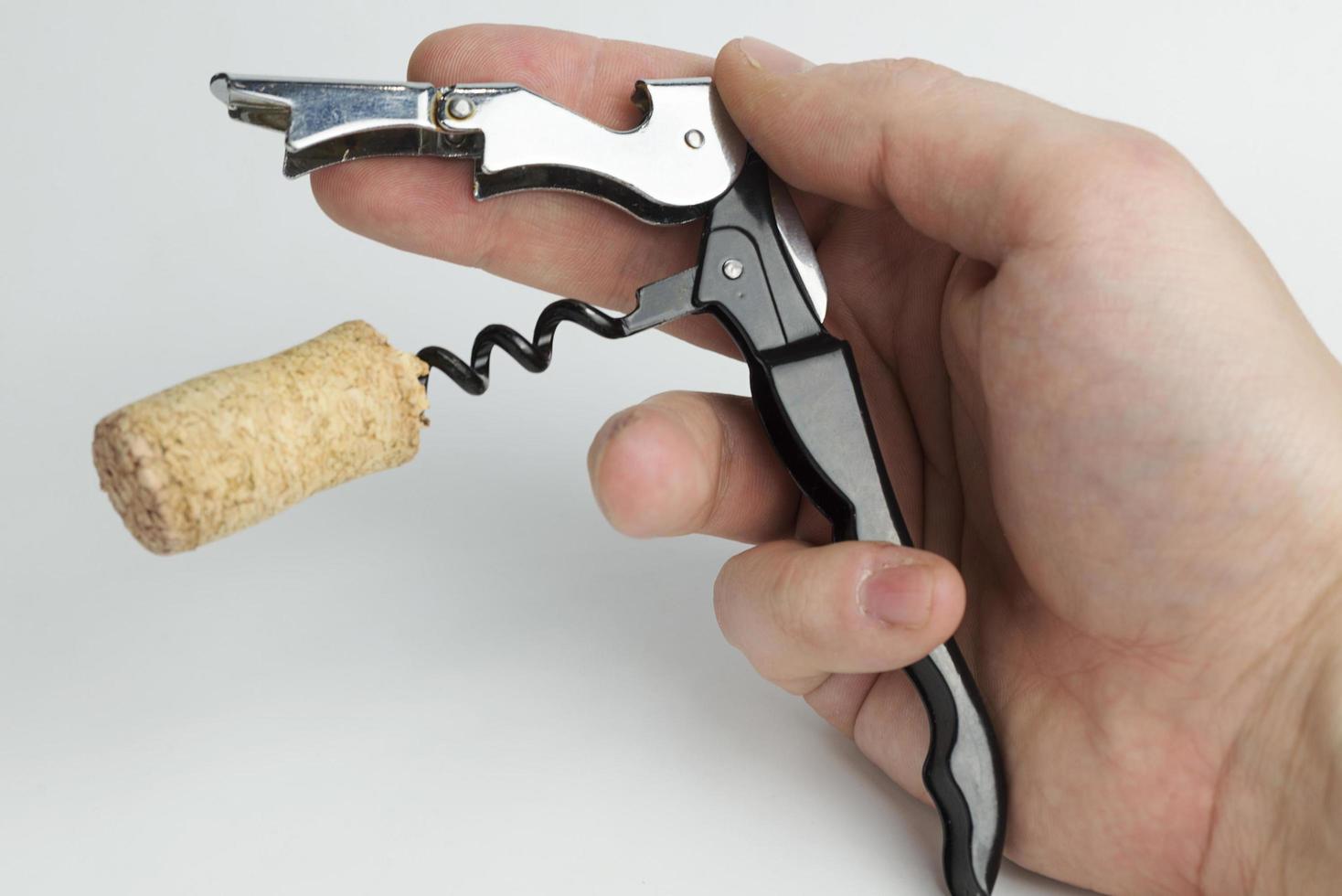 The hand holding the corkscrew on white background for wine bottles. photo