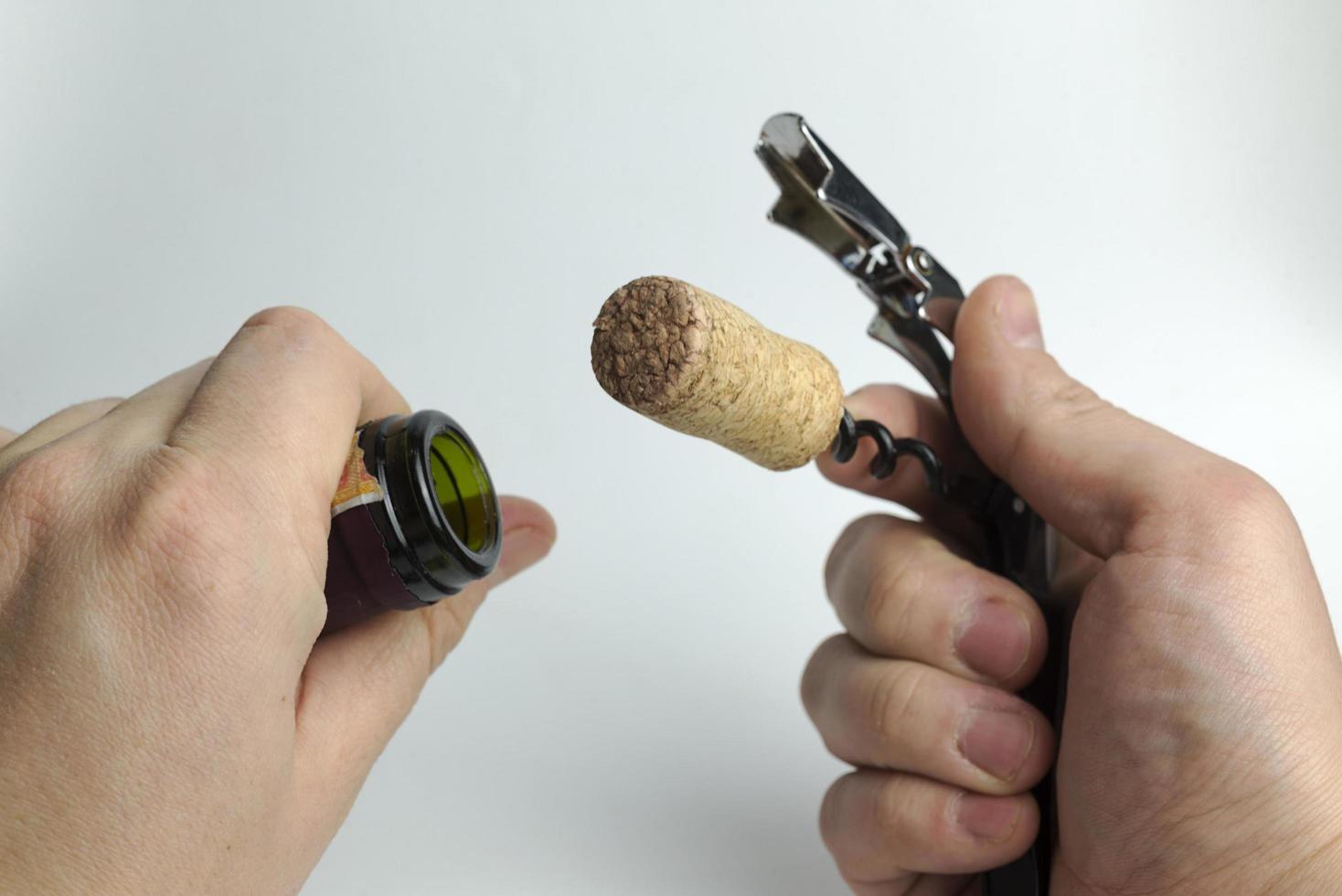 The hand holding the corkscrew on white background for wine bottles. photo