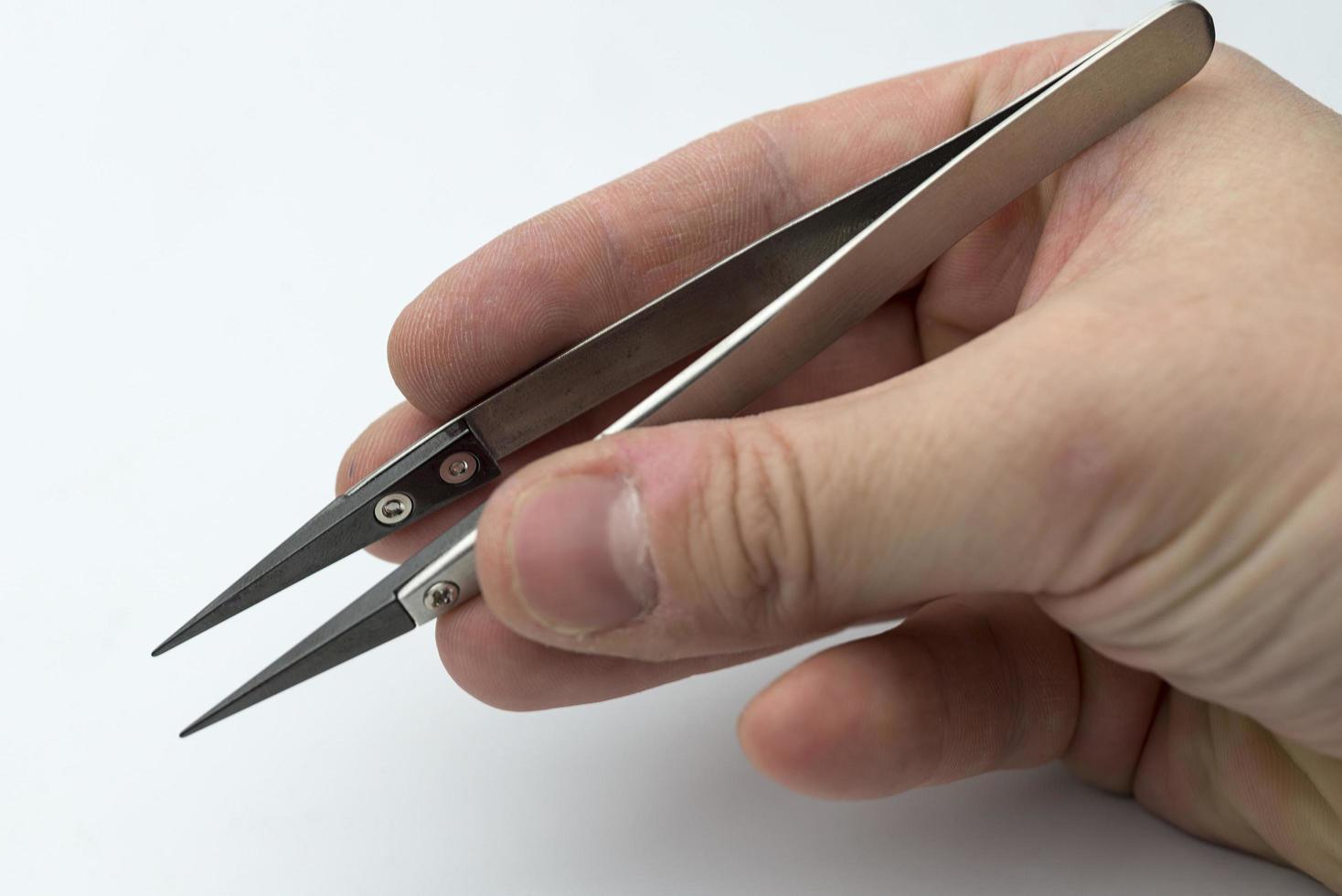 Hand holding a pair of tweezers. photo