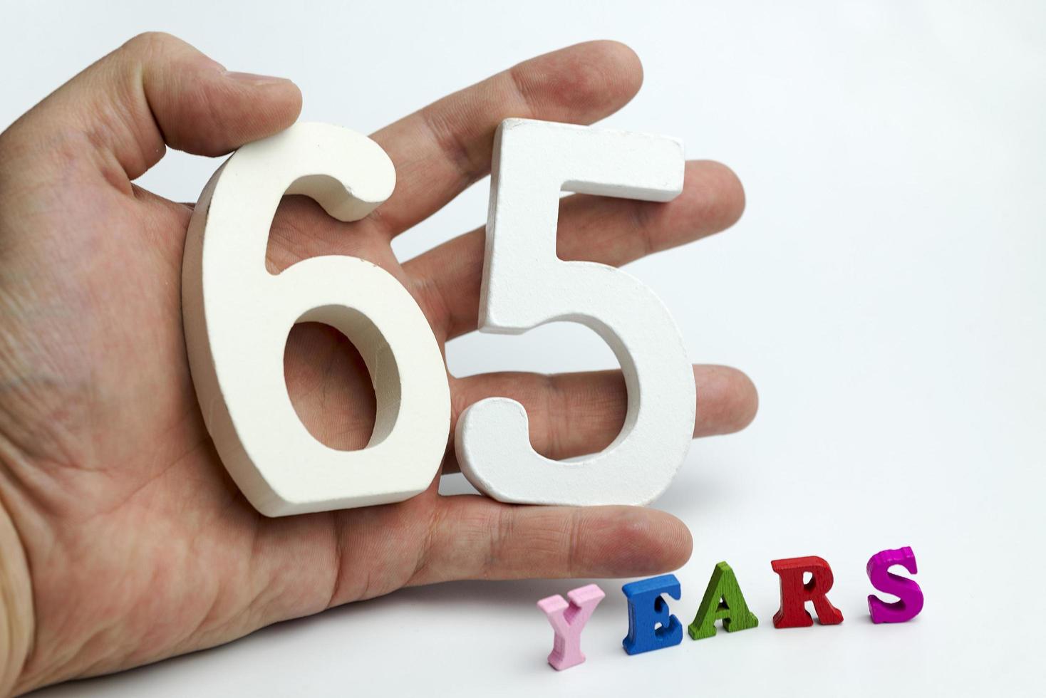 Hand holds a figure of sixty-five. photo