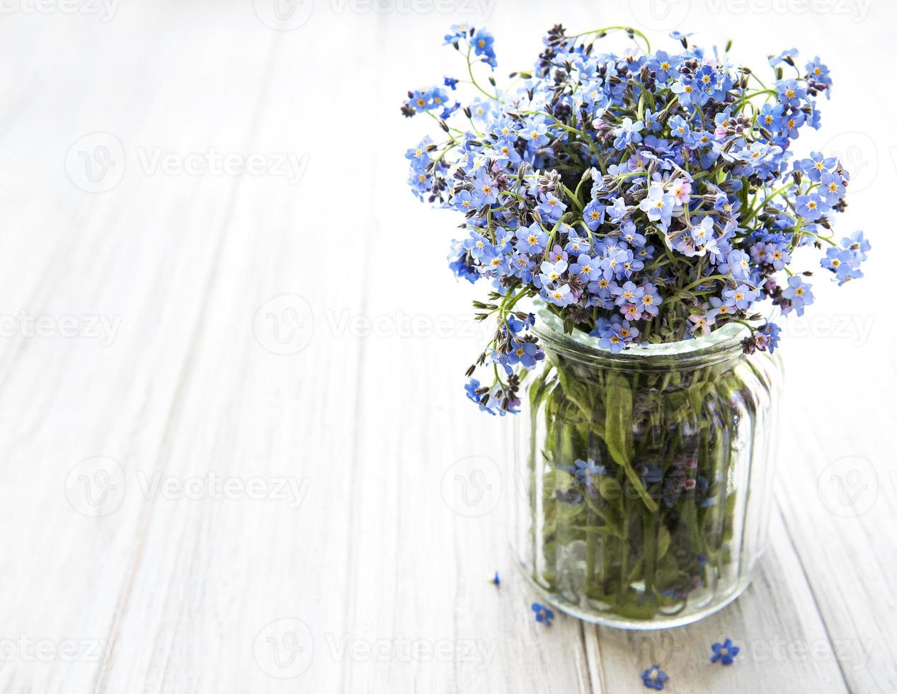 Bouquet of forget-me-not flowers in glass vase photo