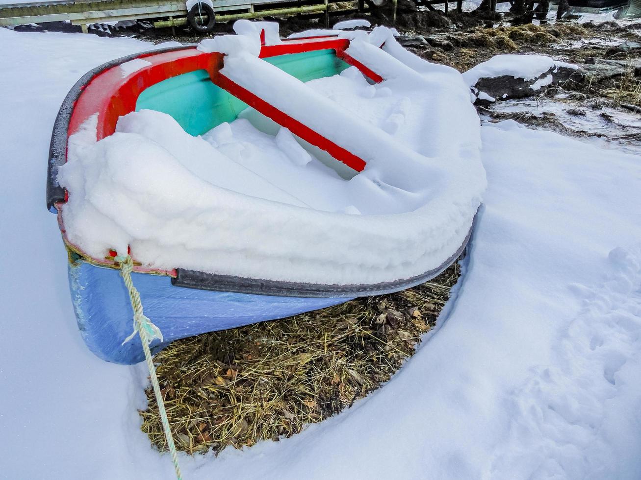 Colorful snow-covered boat on coast by the fjord, Norway. photo