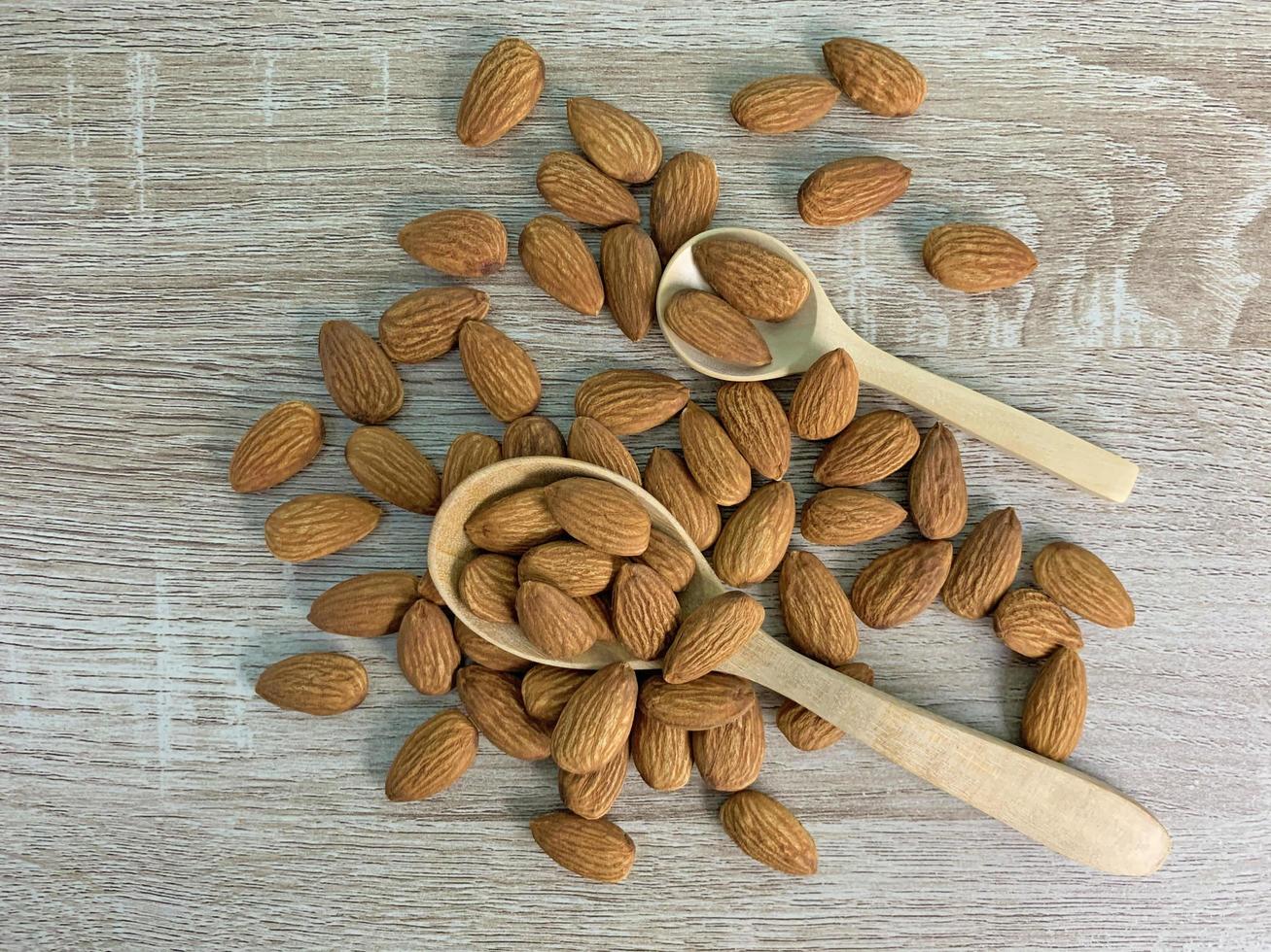 almendras en mesa de madera, almendras en cuchara de madera. foto