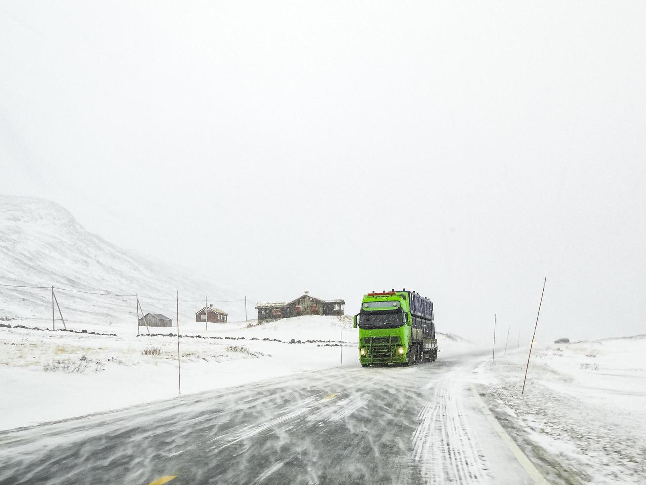 conduciendo a través del paisaje nevado de la carretera, noruega. camión verde al frente. foto