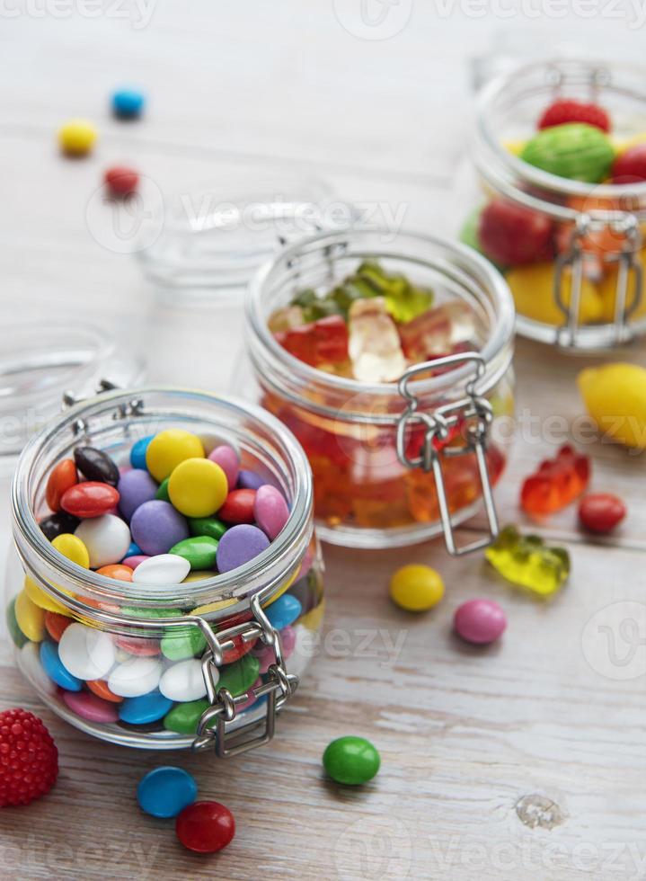 Colorful candies in jars on table photo