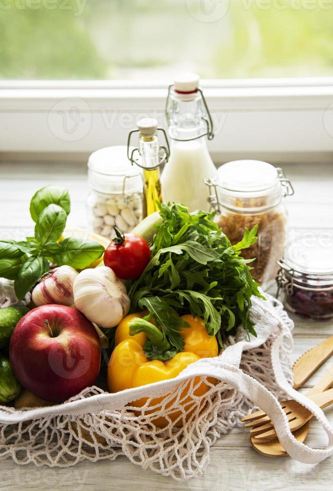 Zero waste concept. Eco bag with fruits and vegetables, glass jars with beans,  pasta. Eco-friendly shopping and cooking concept, flat lay photo