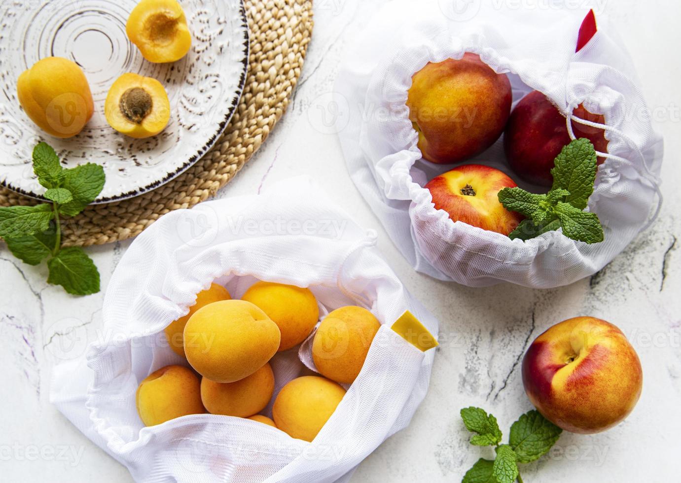 Peaches and apricots in eco bags. photo