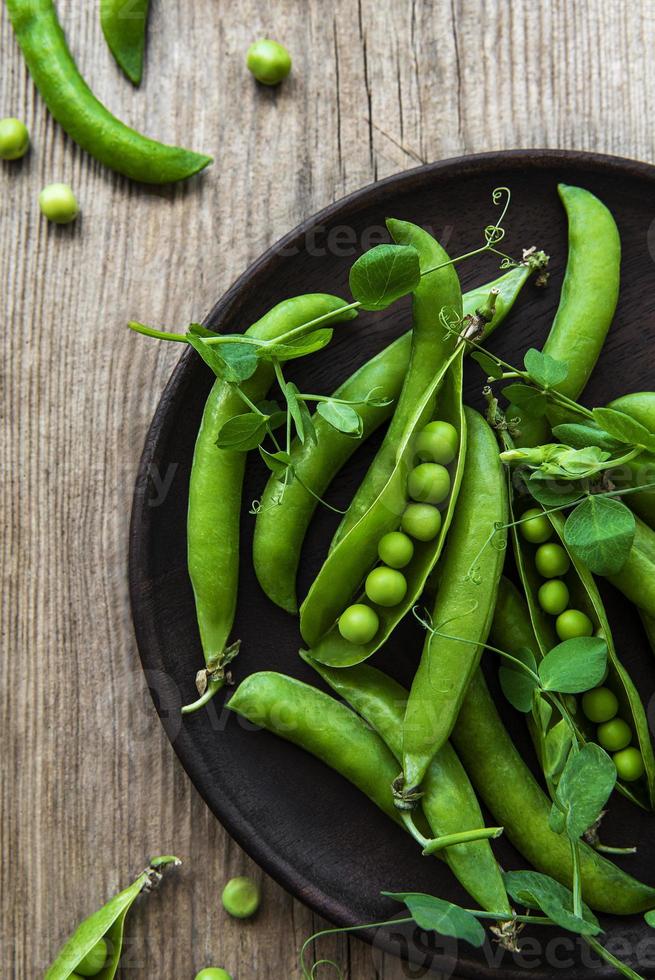 Green peas in a plate on a old wooden  background. View from above. photo