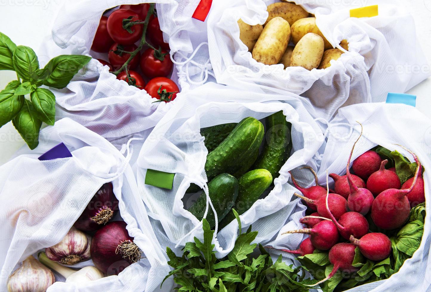 Mesh shopping bag with organic vegetables on marble background. Flat lay, top view. Zero waste, plastic free concept.  Summer fruits. photo