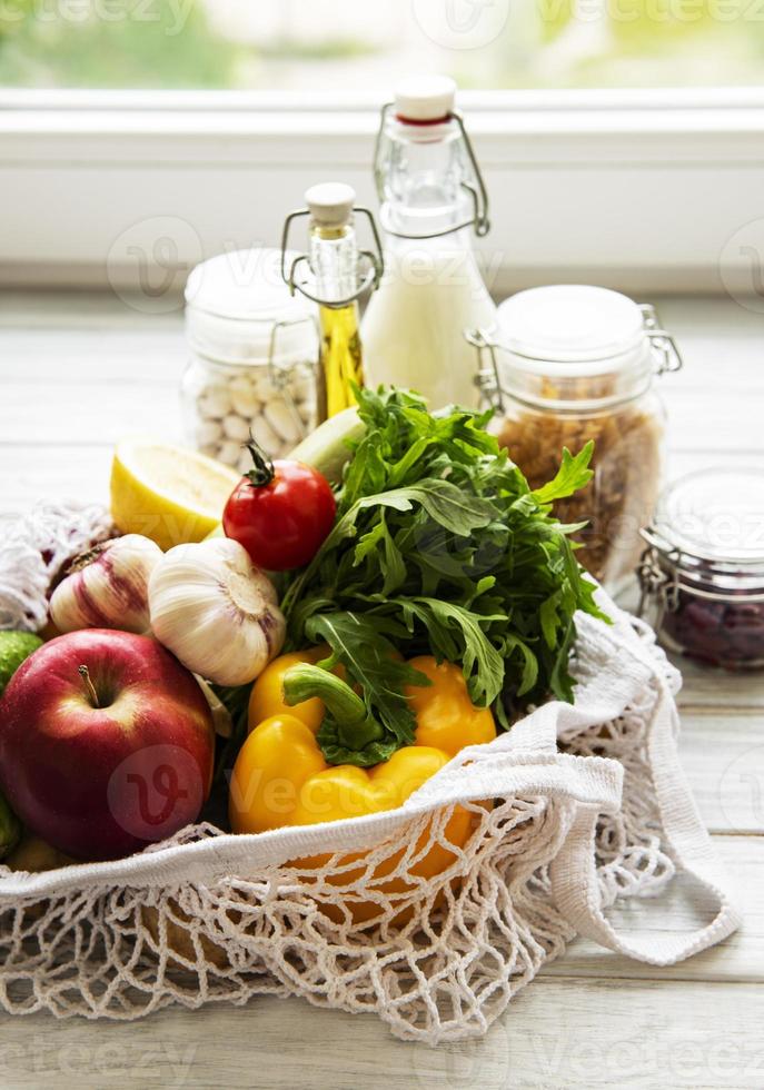 Zero waste concept. Eco bag with fruits and vegetables, glass jars with beans,  pasta. Eco-friendly shopping and cooking concept, flat lay photo