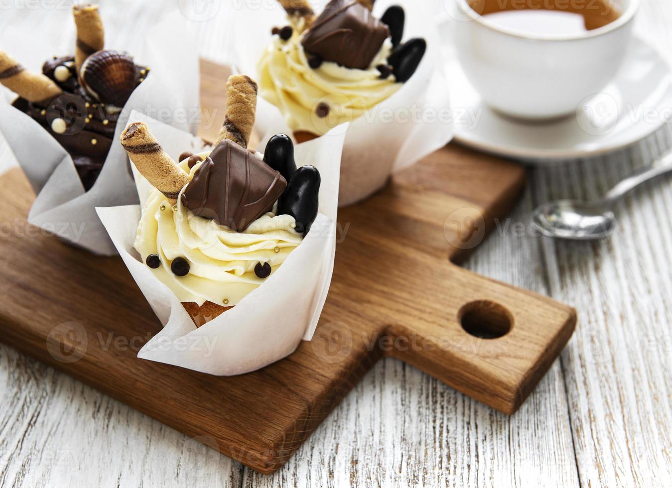 Chocolate cupcakes and cup of tea on white wooden background photo