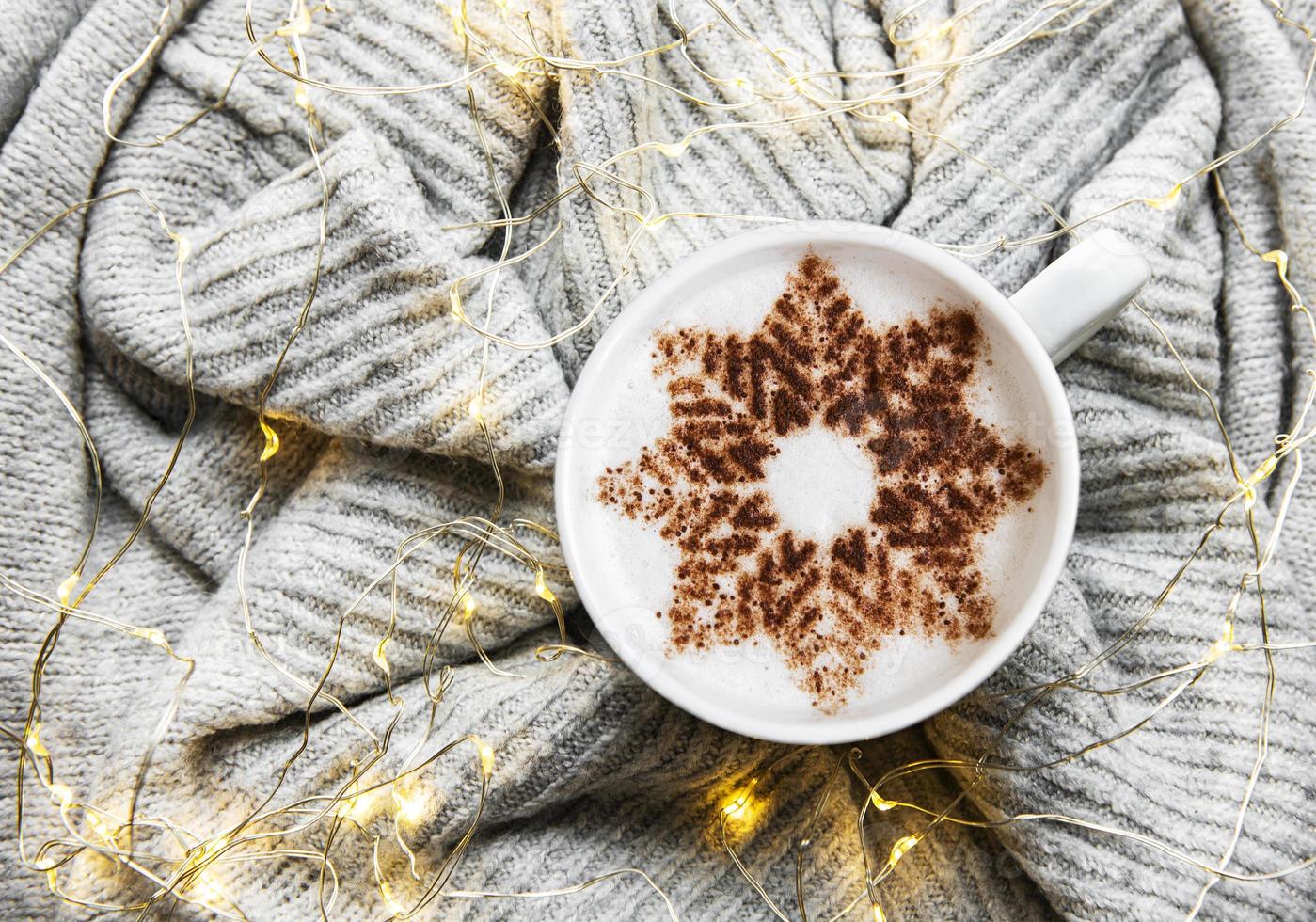 Coffee with a snowflake pattern on a warm knitted sweater photo