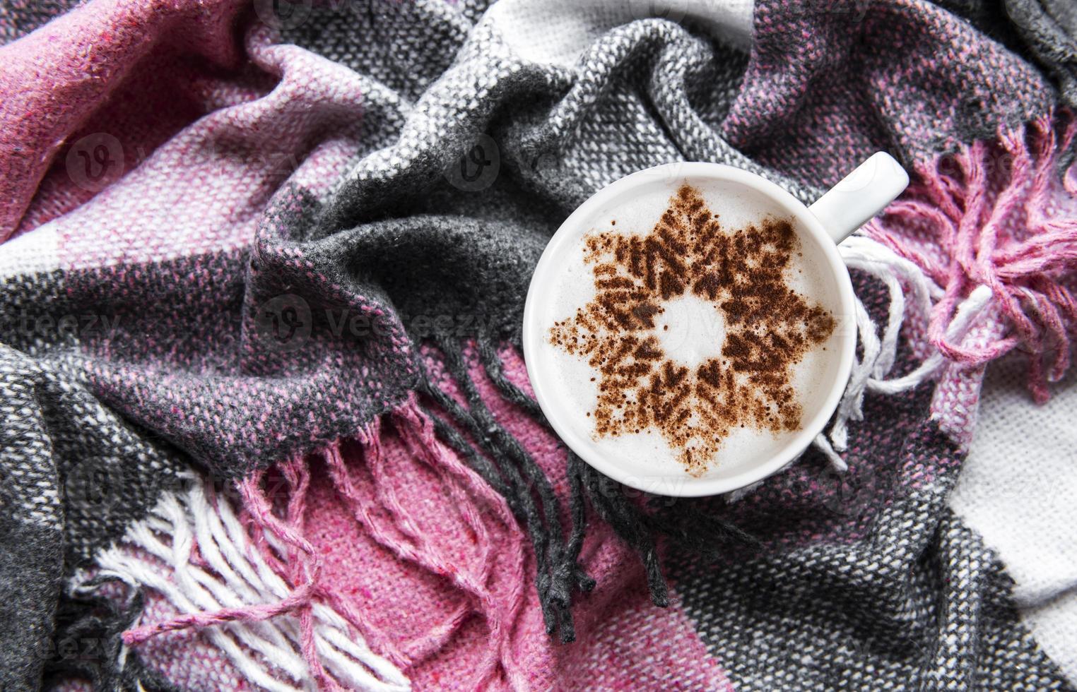 Coffee with a snowflake pattern on a warm woolen plaid photo