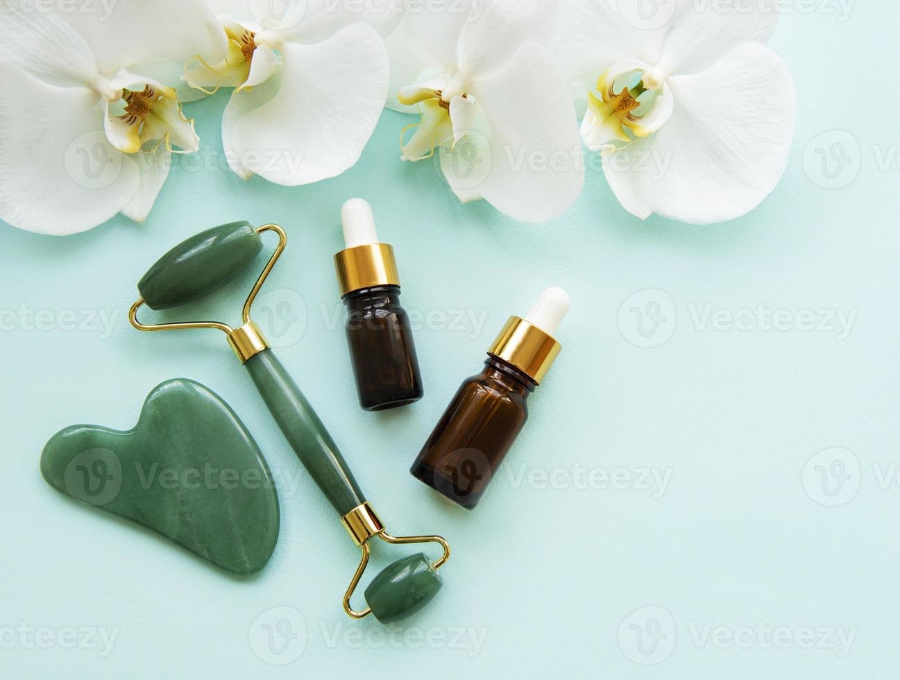rodillo de jade de masaje facial con producto cosmético foto