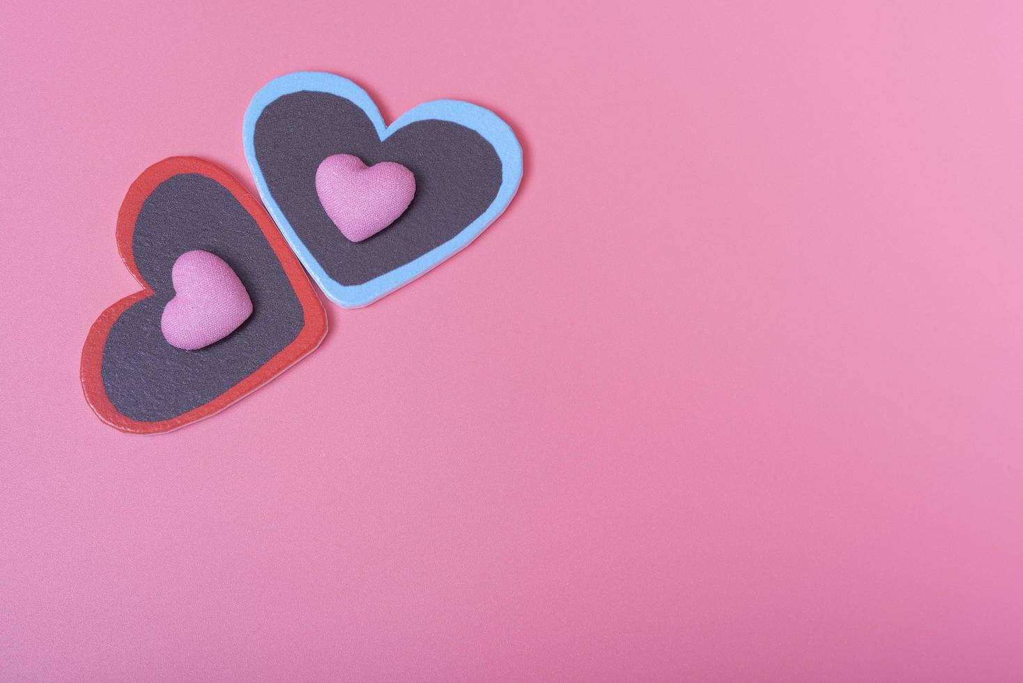 dos corazones sobre fondo rosa en la esquina superior izquierda y dos corazones pequeños. el concepto del día de san valentín. foto