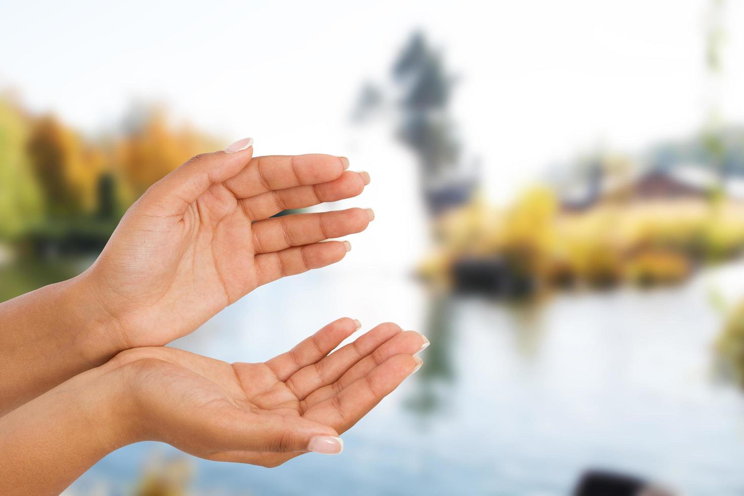 black female hand two palm up, handbreadth isolated on blurred river background. Front view. Mock up. Copy space photo