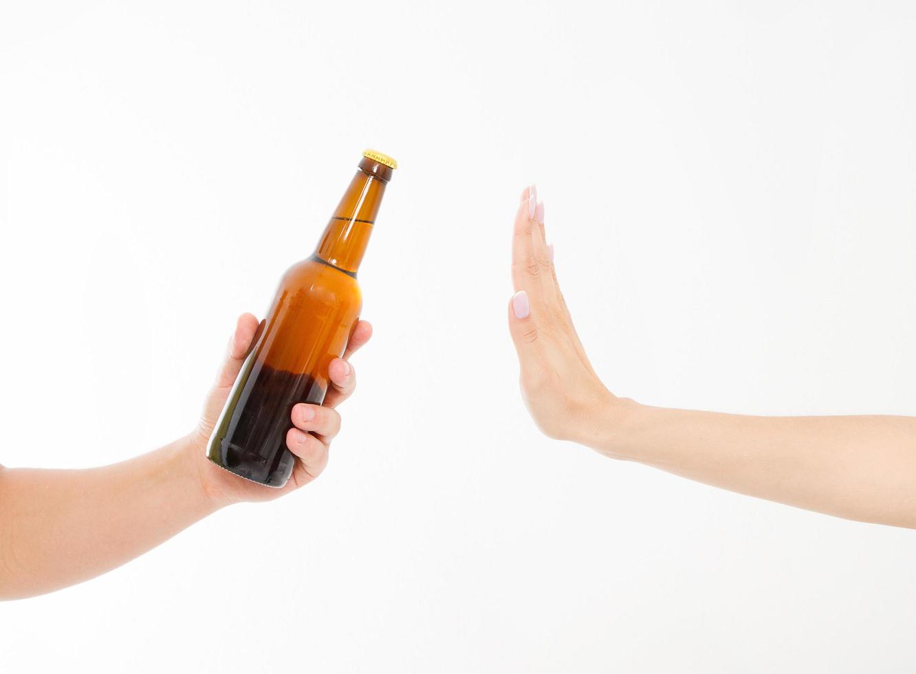 mano femenina rechazar una botella de cerveza aislado sobre fondo blanco concepto anti alcohol. copia espacio foto