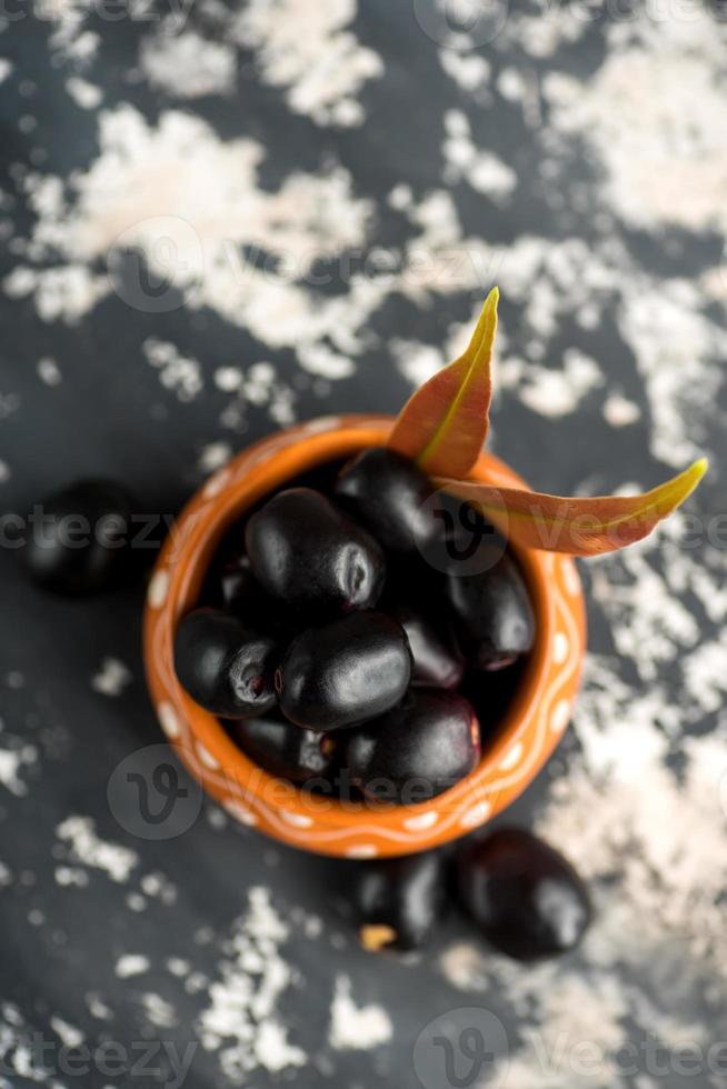 Jambolan plum or jambul or Jamun fruit, Java plum with leaf on stone textured background. photo