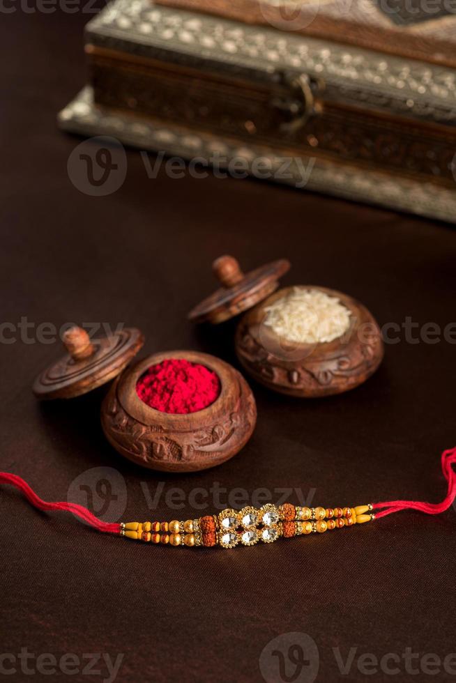 Indian festival Raksha Bandhan background with an elegant Rakhi, Rice Grains and Kumkum. A traditional Indian wrist band which is a symbol of love between Brothers and Sisters. photo