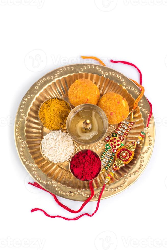 Indian Festival Rakhi with rice grains, kumkum, sweets and diya on plate with an elegant Rakhi. A traditional Indian wrist band which is a symbol of love between Brothers and Sisters photo