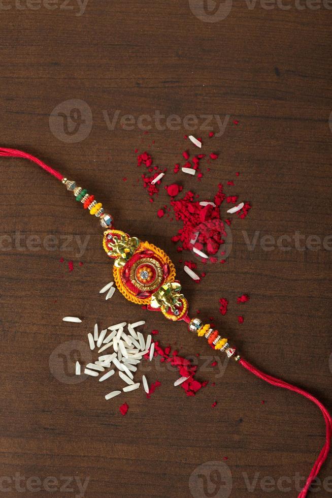 Indian festival Raksha Bandhan background with an elegant Rakhi, Rice Grains and Kumkum. A traditional Indian wrist band which is a symbol of love between Brothers and Sisters. photo