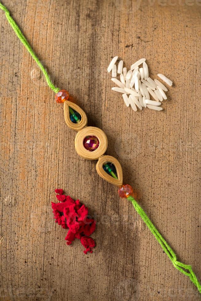Indian festival Raksha Bandhan background with an elegant Rakhi, Rice Grains and Kumkum. A traditional Indian wrist band which is a symbol of love between Brothers and Sisters. photo