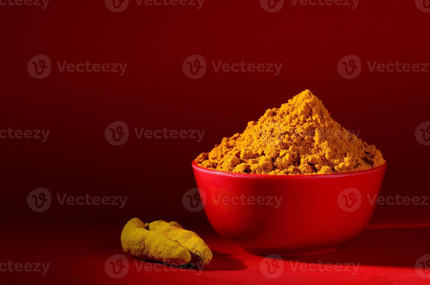 Dry Turmeric powder and roots or barks in red bowl on red background photo