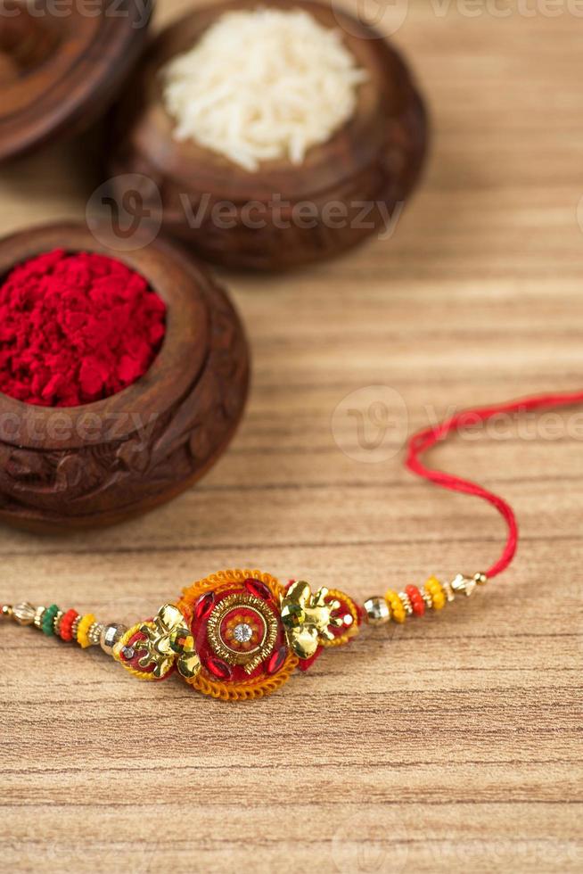 Indian festival Raksha Bandhan background with an elegant Rakhi, Rice Grains and Kumkum. A traditional Indian wrist band which is a symbol of love between Brothers and Sisters. photo