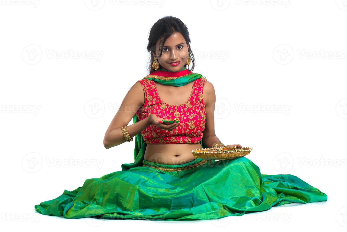 Portrait of a Indian Traditional Girl holding Diya, Girl Celebrating Diwali or Deepavali with holding oil lamp during festival of light on white background photo