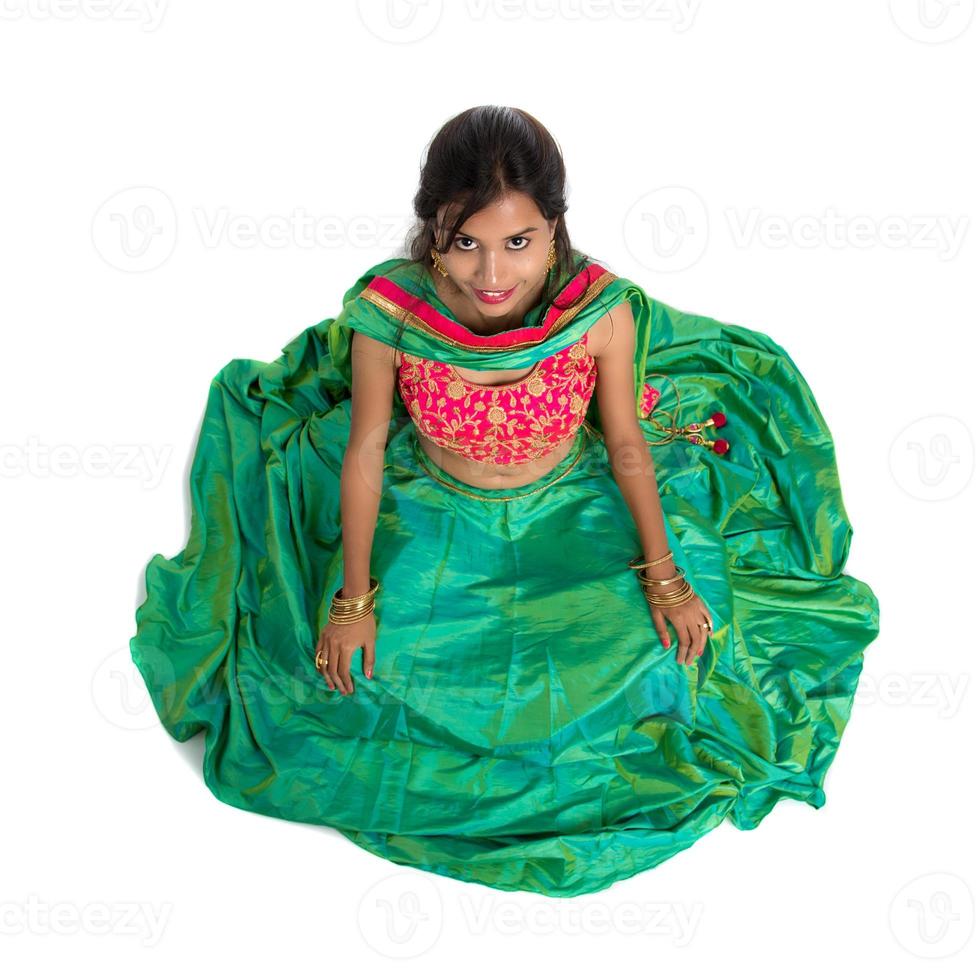 Beautiful Indian traditional girl sitting and posing on white background. photo