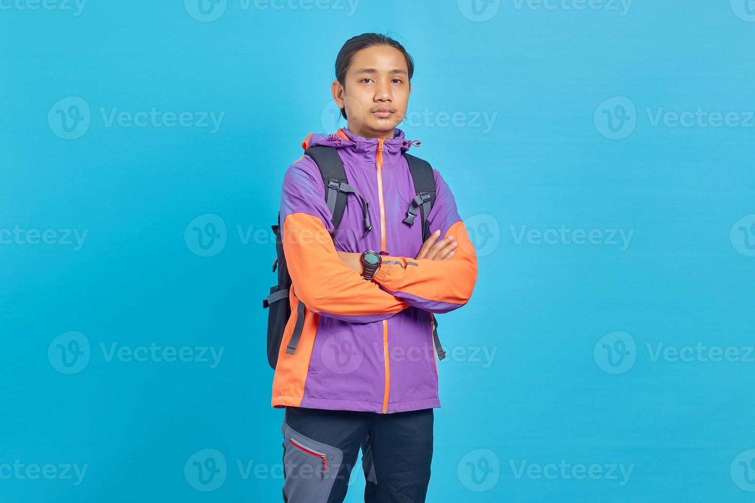 Smiling young Asian man with crossed arms looking at camera on blue background photo