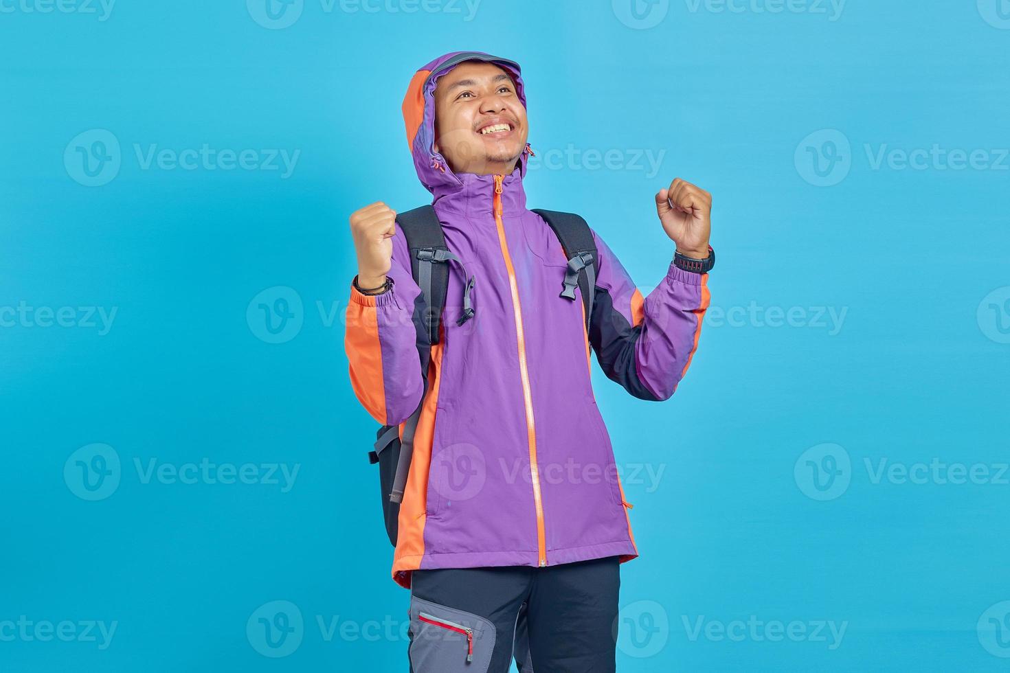Retrato de un joven asiático emocionado celebrando el éxito sobre fondo azul. foto