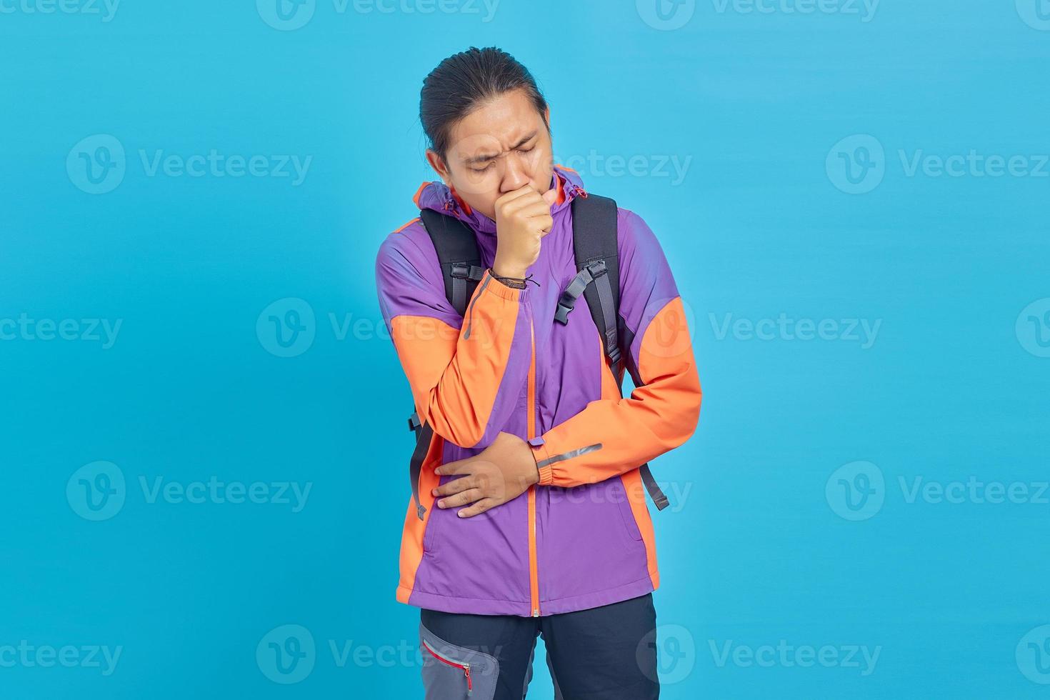 Portrait of handsome Asian man feeling unwell and coughing on blue background photo