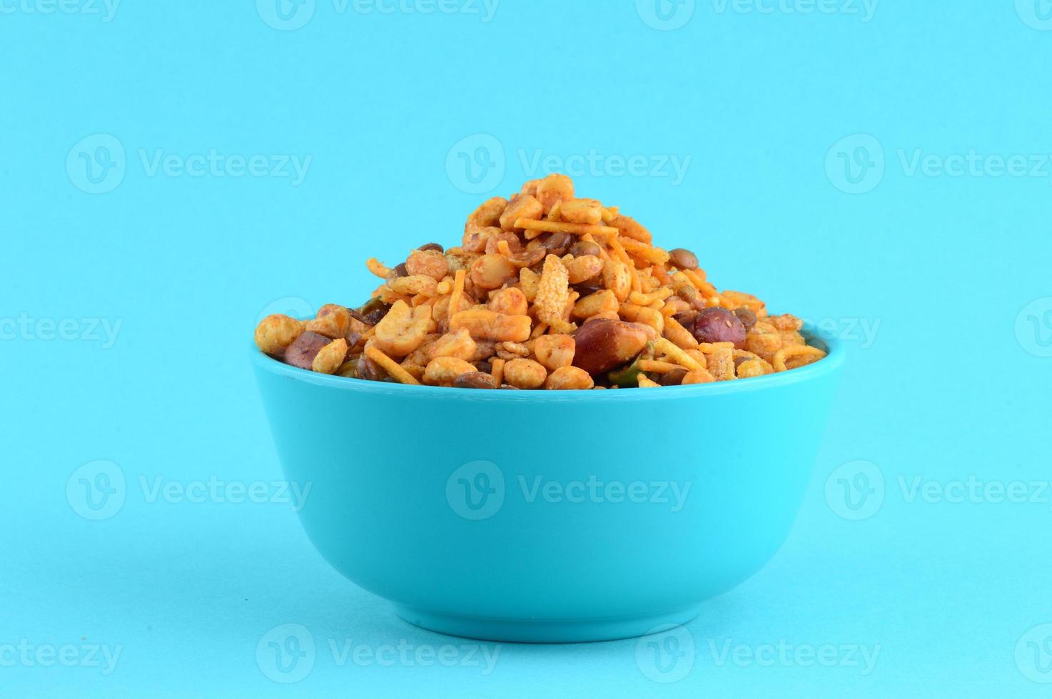 Indian Snacks Mixture roasted nuts with salt pepper masala, pulses, channa masala dal green peas in blue bowl in photo