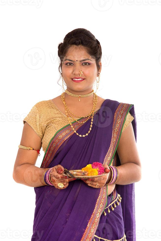 Retrato de una niña tradicional india sosteniendo pooja thali con foto diya, diwali o deepavali con manos femeninas sosteniendo una lámpara de aceite durante el festival de la luz sobre fondo blanco.