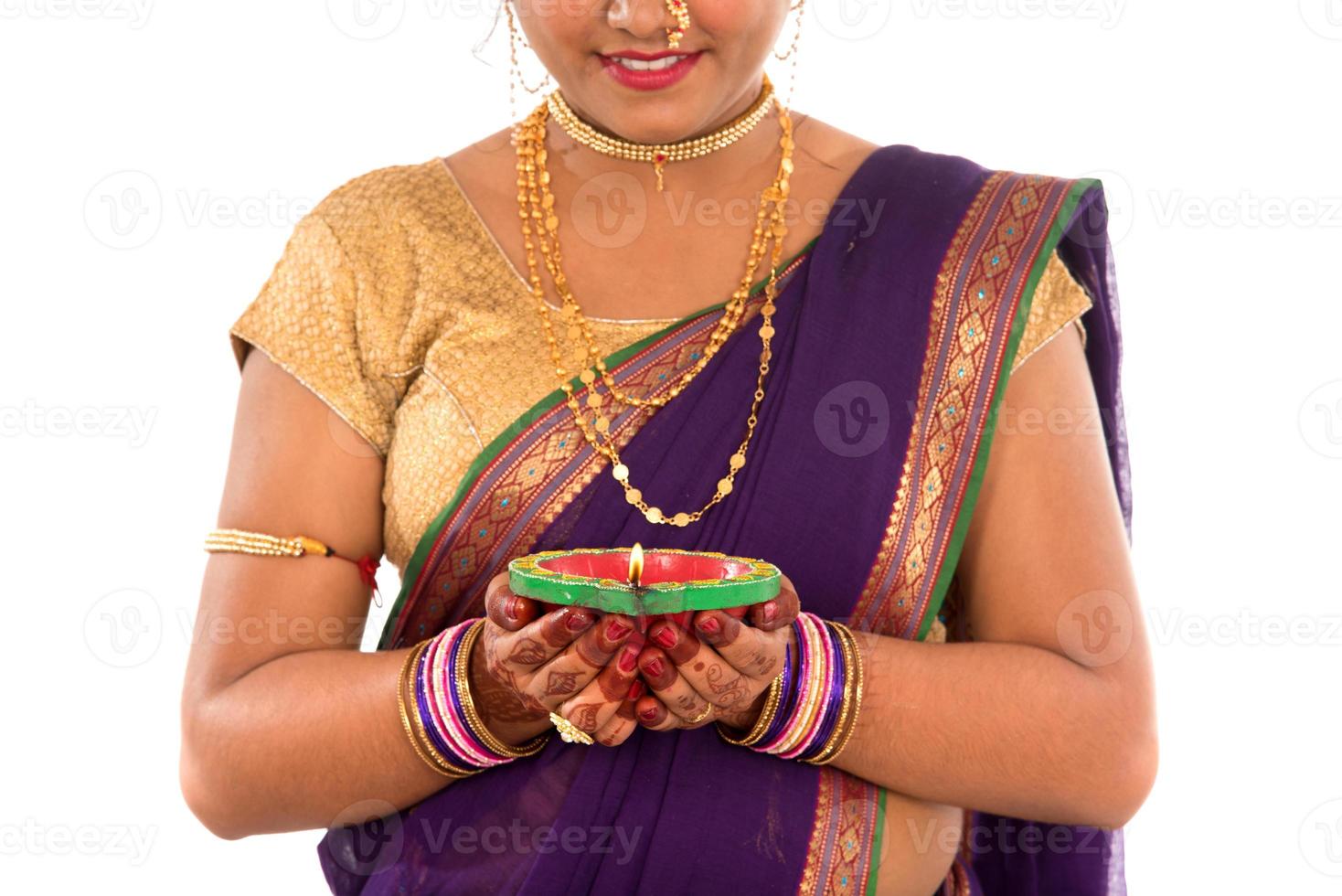 Retrato de una niña tradicional india sosteniendo una foto de diya, diwali o deepavali con manos femeninas sosteniendo una lámpara de aceite durante el festival de la luz sobre fondo blanco.