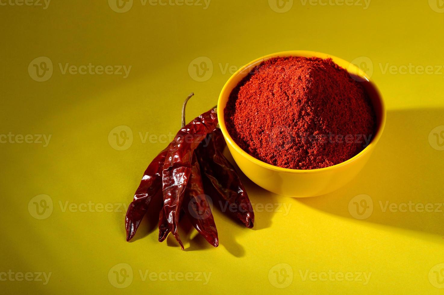 chili powder in yellow bowl on yellow background. Red chilly pepper photo