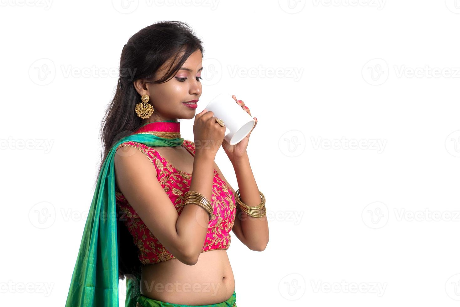 Hermosa joven con una taza de té o café posando sobre fondo blanco. foto