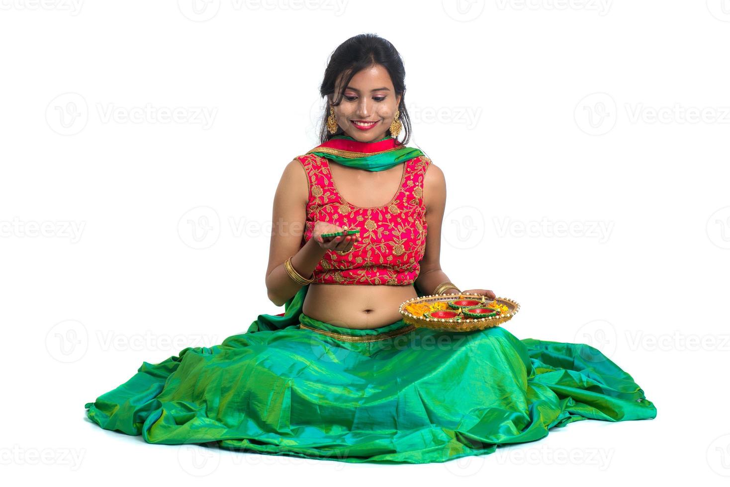 Retrato de una niña tradicional india sosteniendo diya, niña celebrando el diwali o deepavali con la celebración de la lámpara de aceite durante el festival de la luz sobre fondo blanco. foto