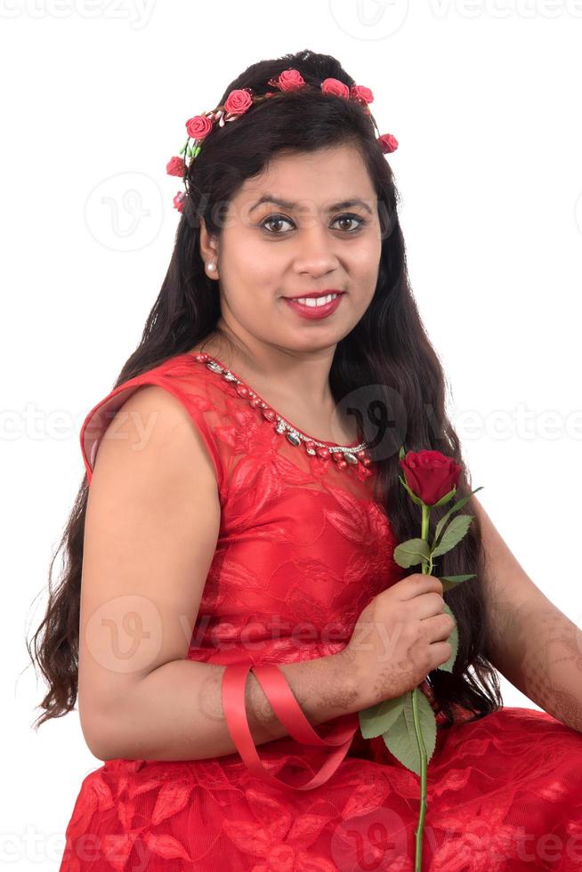 Beautiful young girl or woman holding and posing with red rose flower on white background photo