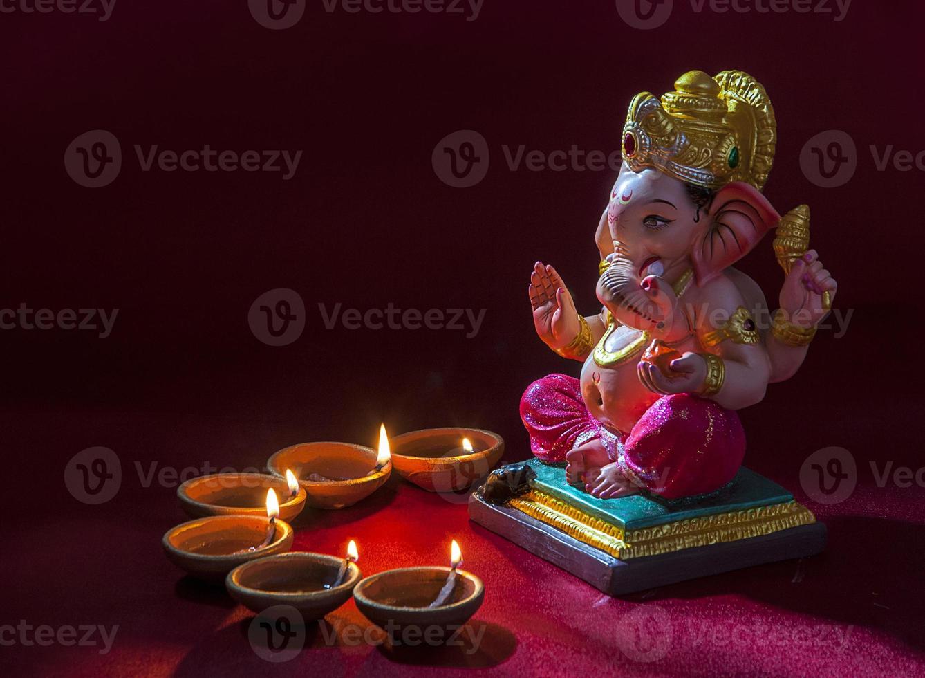 Clay diya lamps lit with Lord Ganesha during Diwali Celebration. Greetings Card Design Indian Hindu Light Festival called Diwali photo