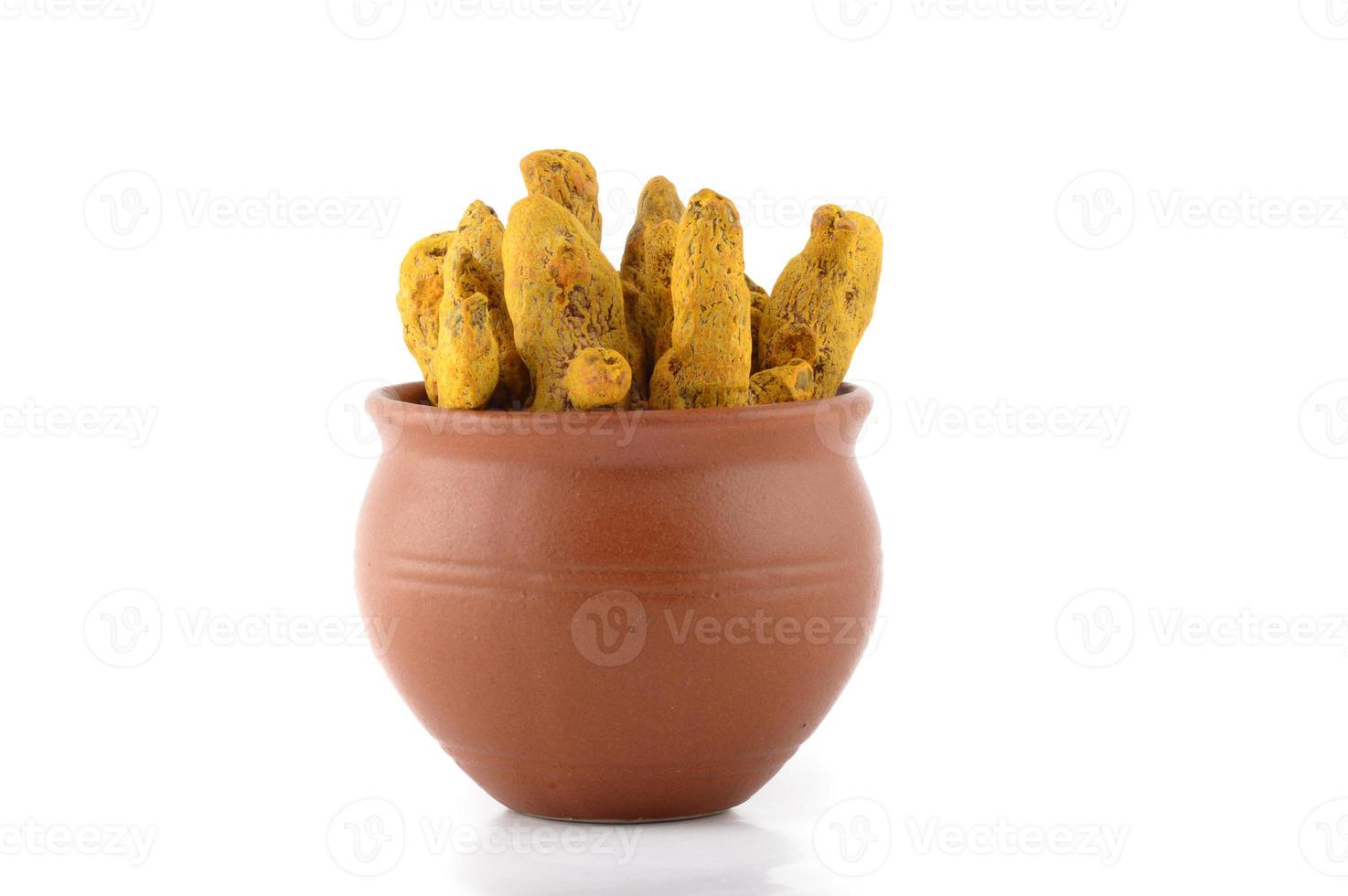 Dry Turmeric roots or barks in clay pot isolated on white background photo
