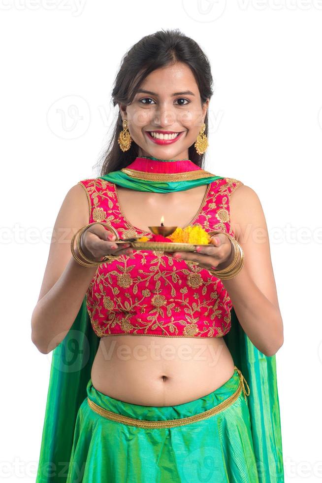 Hermosa joven india sosteniendo pooja thali o realizando adoración sobre un fondo blanco. foto