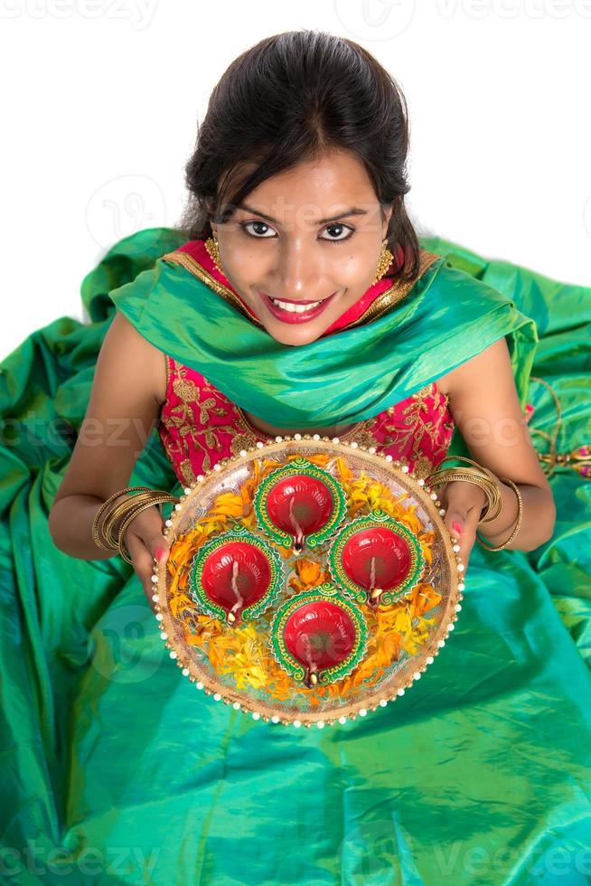 Retrato de una niña tradicional india sosteniendo diya, niña celebrando el diwali o deepavali con la celebración de la lámpara de aceite durante el festival de la luz sobre fondo blanco. foto