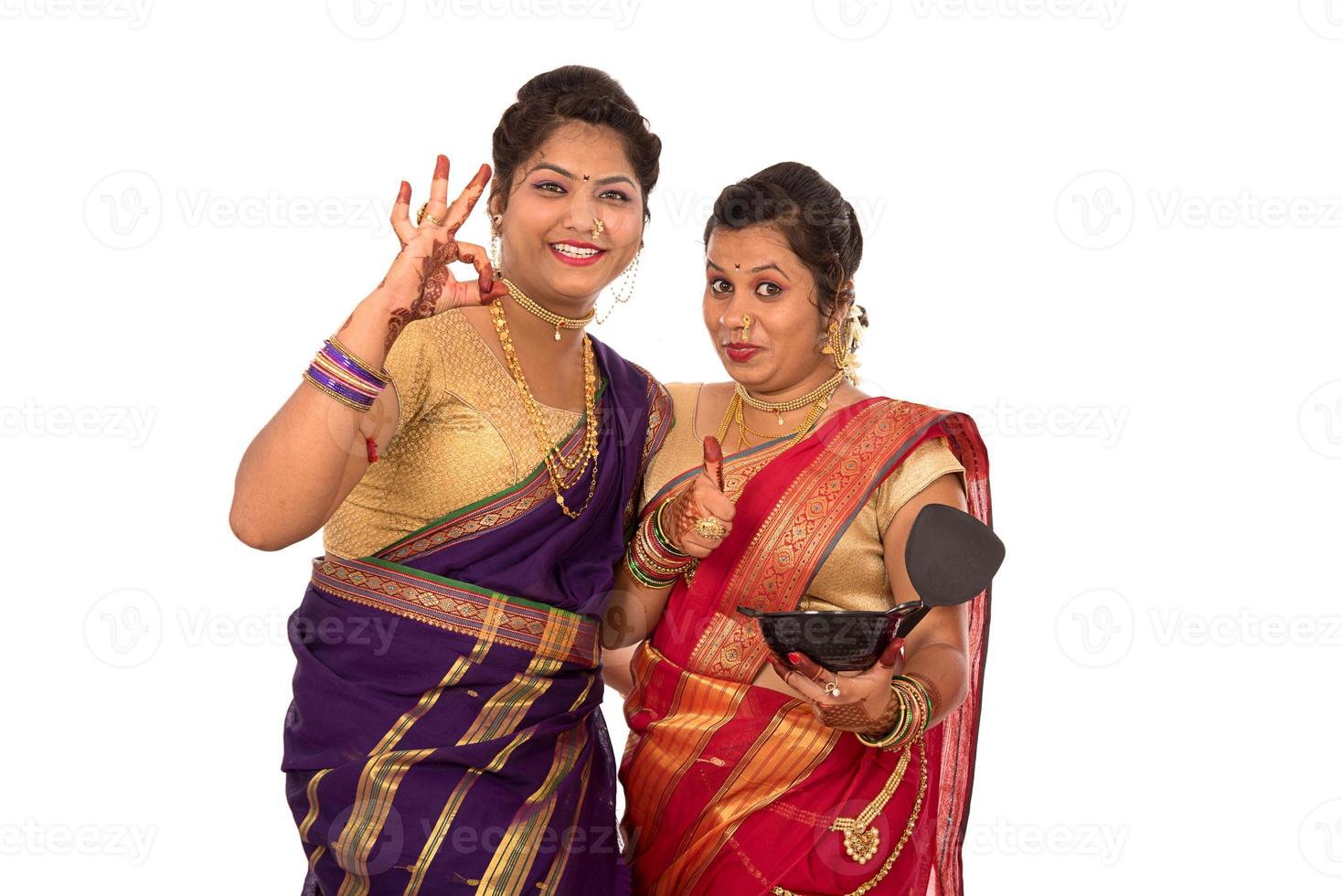 Jóvenes muchachas indias tradicionales sosteniendo utensilios de cocina sobre fondo blanco. foto