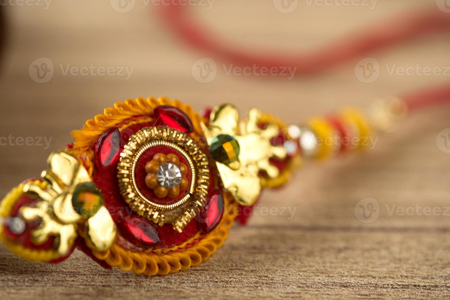 Indian festival Raksha Bandhan background with an elegant Rakhi, Rice Grains and Kumkum. A traditional Indian wrist band which is a symbol of love between Brothers and Sisters. photo