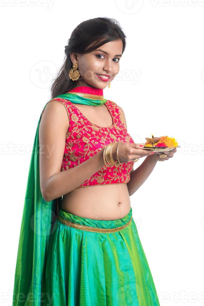 Hermosa joven india sosteniendo pooja thali o realizando adoración sobre un fondo blanco. foto