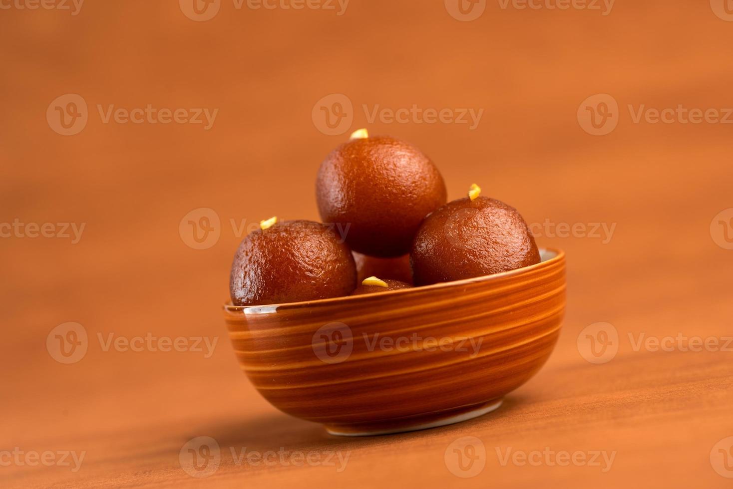 gulab jamun en un tazón sobre fondo de madera. postre indio o plato dulce. foto