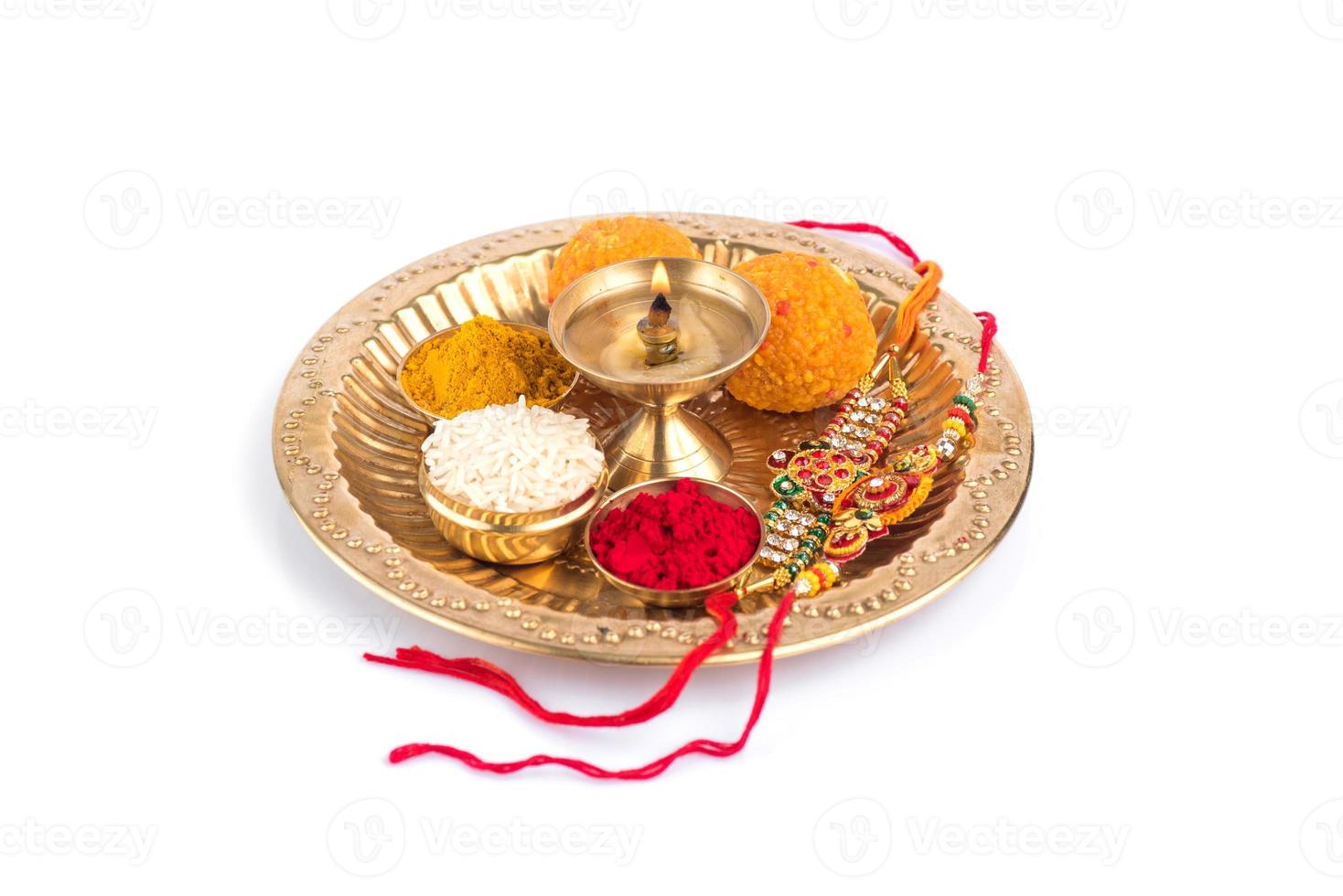 Indian Festival Rakhi with rice grains, kumkum, sweets and diya on plate with an elegant Rakhi. A traditional Indian wrist band which is a symbol of love between Brothers and Sisters photo